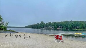 Une plage de sable bordée d’un lac, une rangée de canots jaunes et un panneau rouge orné d’un symbole blanc.