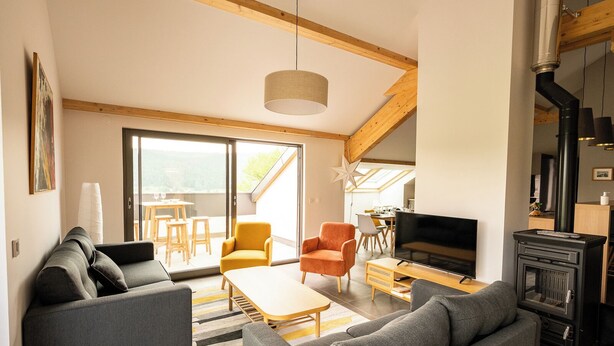 A modern living room with a fireplace, sofa, and dining area.