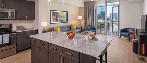 A modern kitchen with dark wood cabinets, a stainless steel microwave, and a granite countertop.