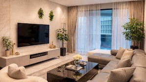 A modern living room with a flat-screen TV, a sofa, a coffee table, and two potted plants. - Eaton Residence by crystal  (Kuala Lumpur)