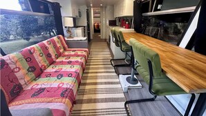 A compact interior with a sofa, bar area, and kitchenette. - The Bello BigRig - Luxury Riverfront Bus Conversion, close to town, pet friendly (Bellingen)