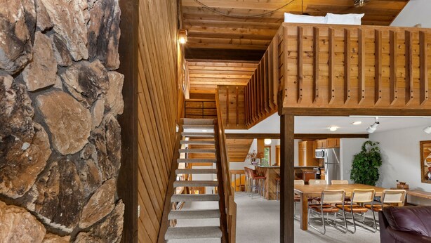 Eine Holztreppe führt zu einem Erkerbereich mit Esstisch und Stühlen.