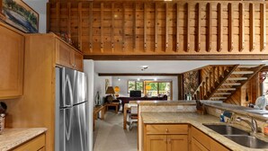 Eine geräumige Küche mit Holzausstattung, einem Edelstahlkühlschrank, einer Granitarbeitsplatte und einer Steinwandverkleidung.