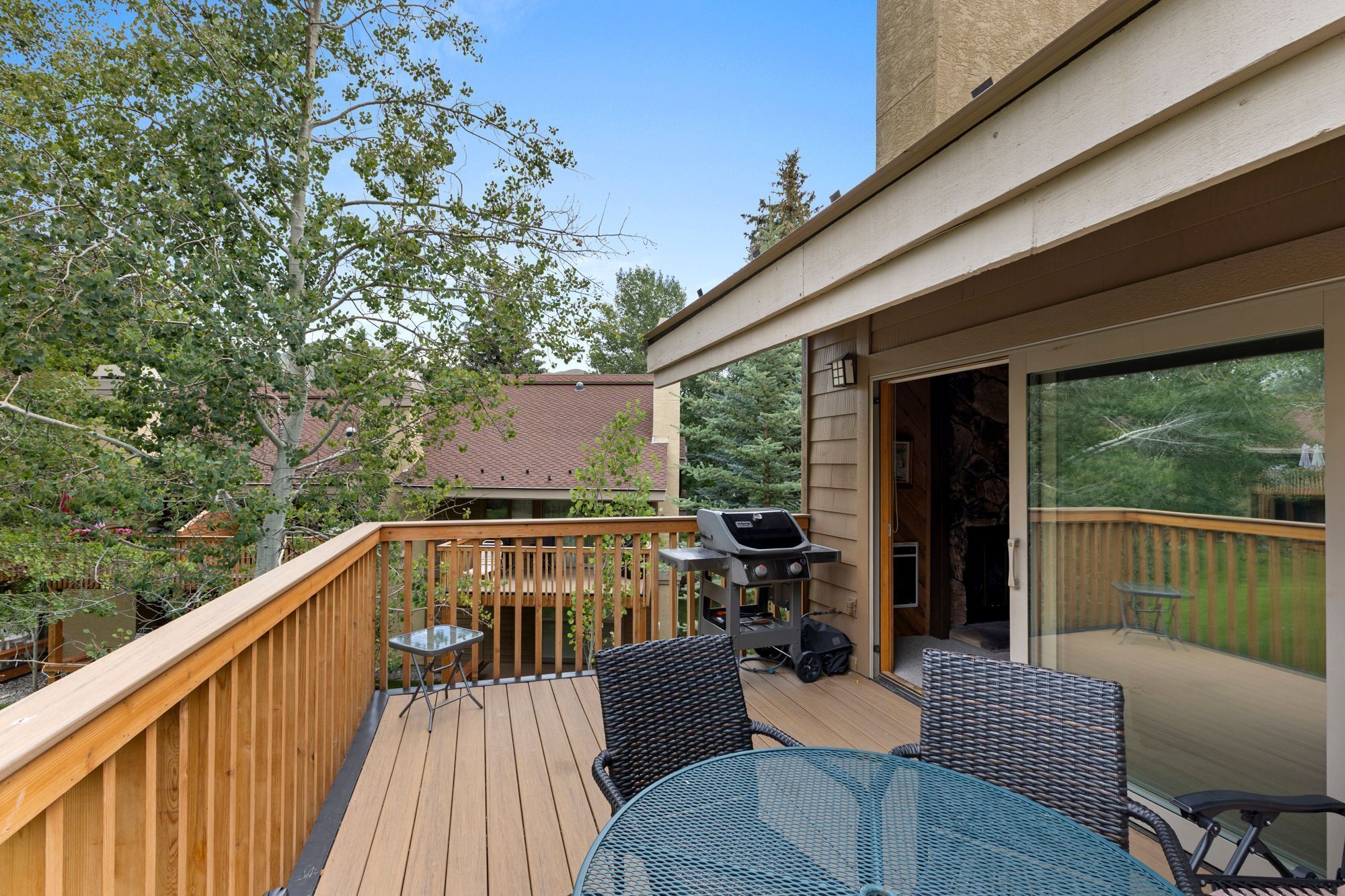 A wooden deck with a glass door leading to a covered patio area.