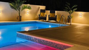 A swimming pool with a tiled edge, surrounded by walls with built-in lighting, and two potted plants. - Jack's Place - by Zenbreak (Mullins)