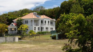 A large white building with multiple windows and a red roof, surrounded by lush greenery. - Jack's Place - by Zenbreak (Mullins)