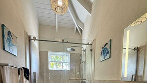 A bathroom with a glass shower enclosure, a toilet, a sink with a mirror, and towels on a rack. - Jack's Place - by Zenbreak (Mullins)