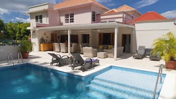 A poolside area with lounge chairs and a covered seating area.