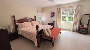 A bedroom with a bed, bedside table, lamp, and a window with curtains.
