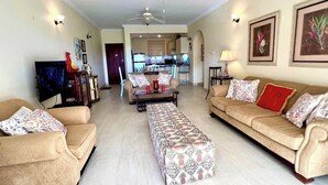 A living room with two sofas, a coffee table, a TV, and a ceiling fan. - Island Time El Sol - by Zenbreak (Durants)