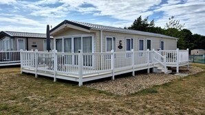 Une maison mobile dotée d’une terrasse blanche et d’un porche abrité.