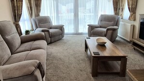 Un salon avec deux fauteuils, une table basse et un téléviseur.