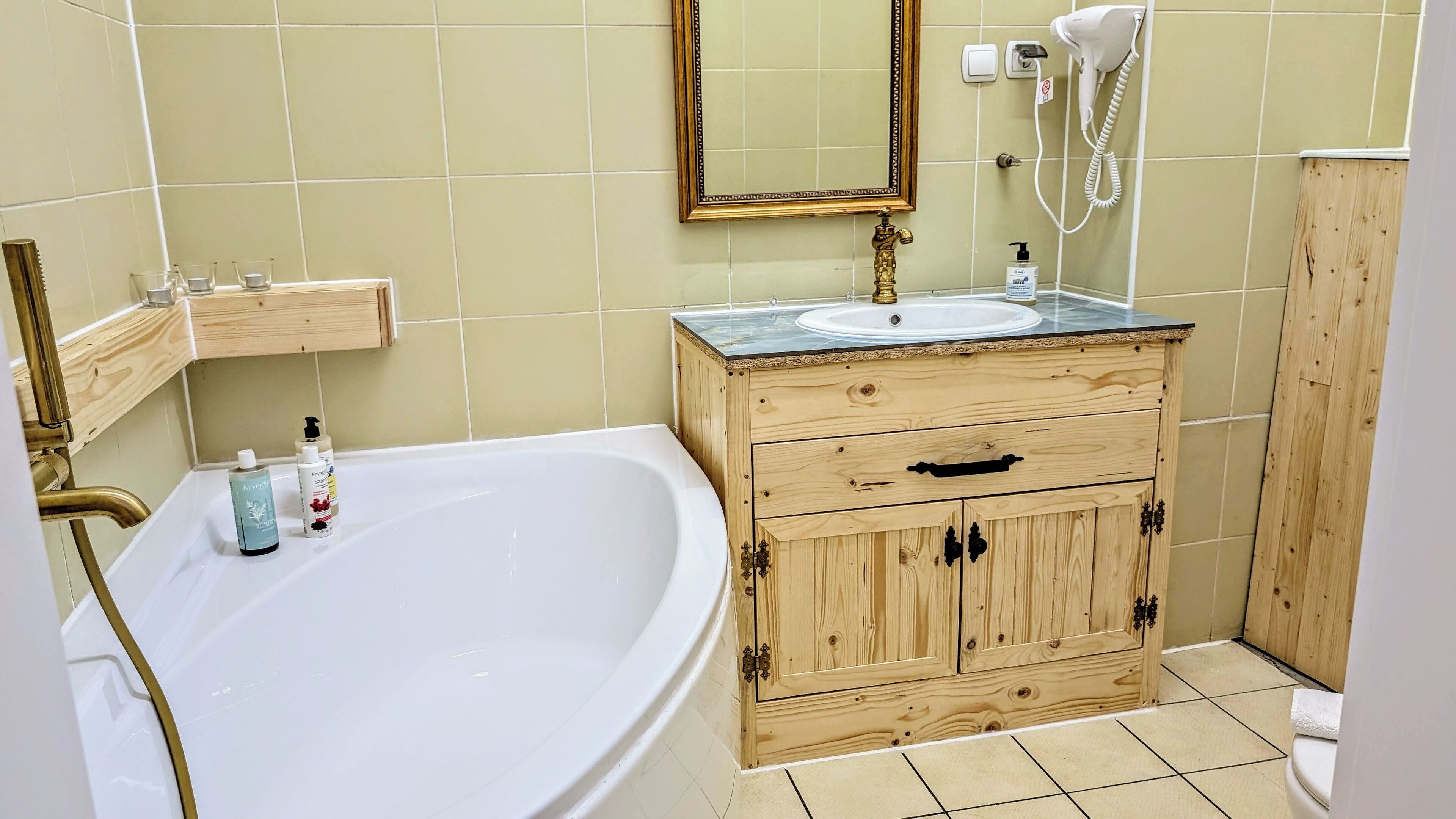 Un baño con bañera, tocador de madera con lavabo y espejo.