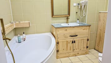 Un baño con bañera, tocador de madera con lavabo y espejo.