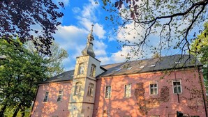 Een historisch gebouw met een opvallende toren en een stenen muur ervoor.