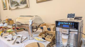 A buffet setup with a self-serve coffee machine, various food items, and dining utensils.