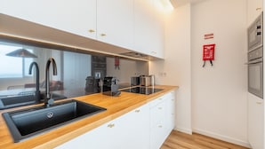 Una cocina moderna con encimera de madera, pileta negra y electrodomésticos de acero inoxidable.