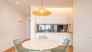 Una cocina moderna con armarios blancos, una mesa redonda y sillas verdes.