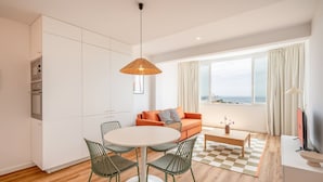 Una sala de estar moderna con una mesa de comedor redonda, un sofá y vista al mar.