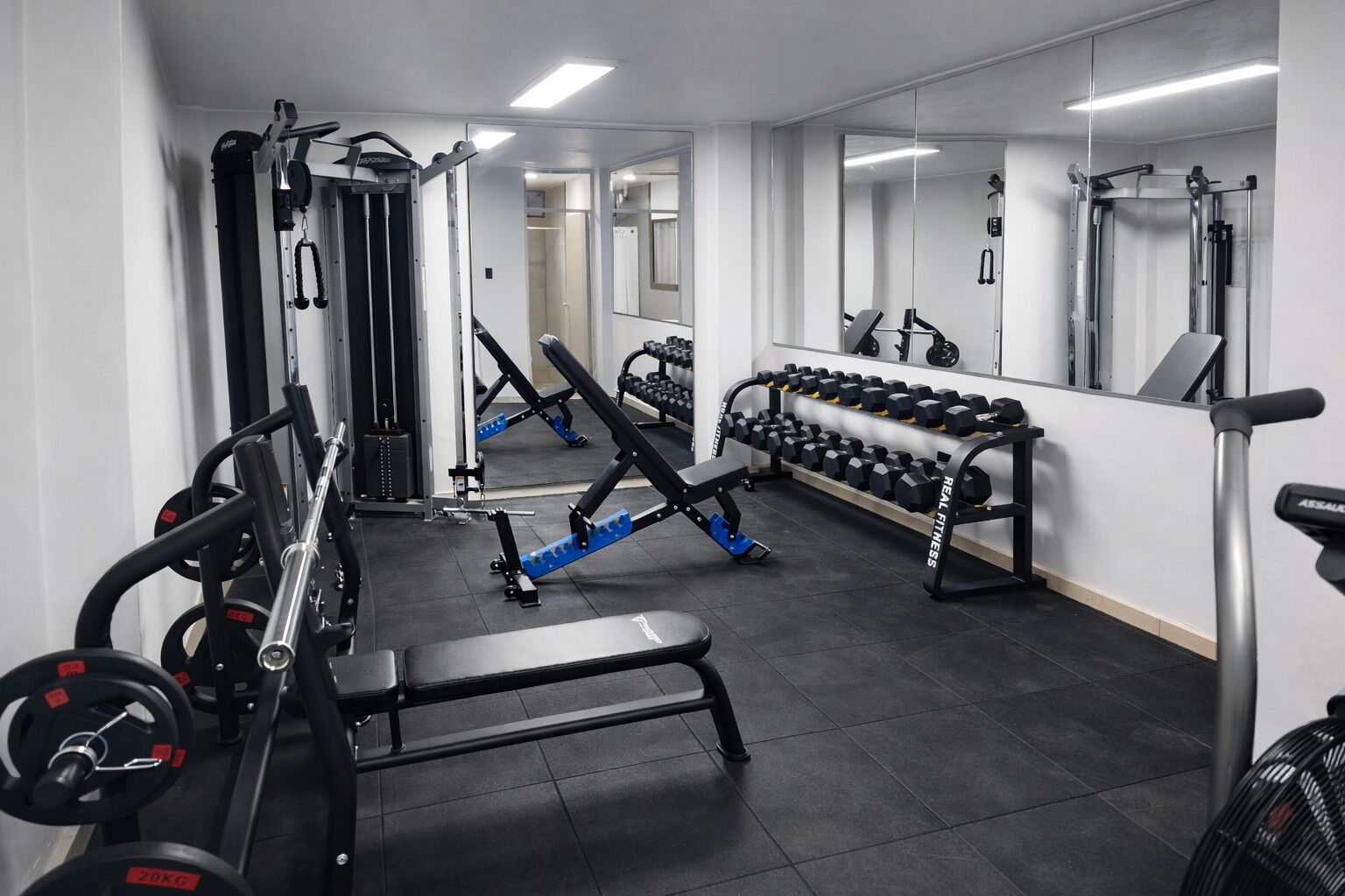 A gym with various exercise equipment, including weight machines, dumbbells, and benches.