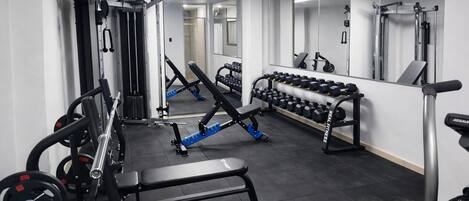 A gym with various exercise equipment, including weight machines, dumbbells, and benches.