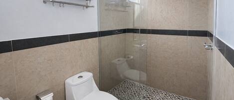 A modern bathroom with a toilet, shower, and patterned floor tiles.