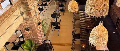 A spacious indoor area with multiple seating arrangements, including tables and chairs, and a staircase leading to an upper level.