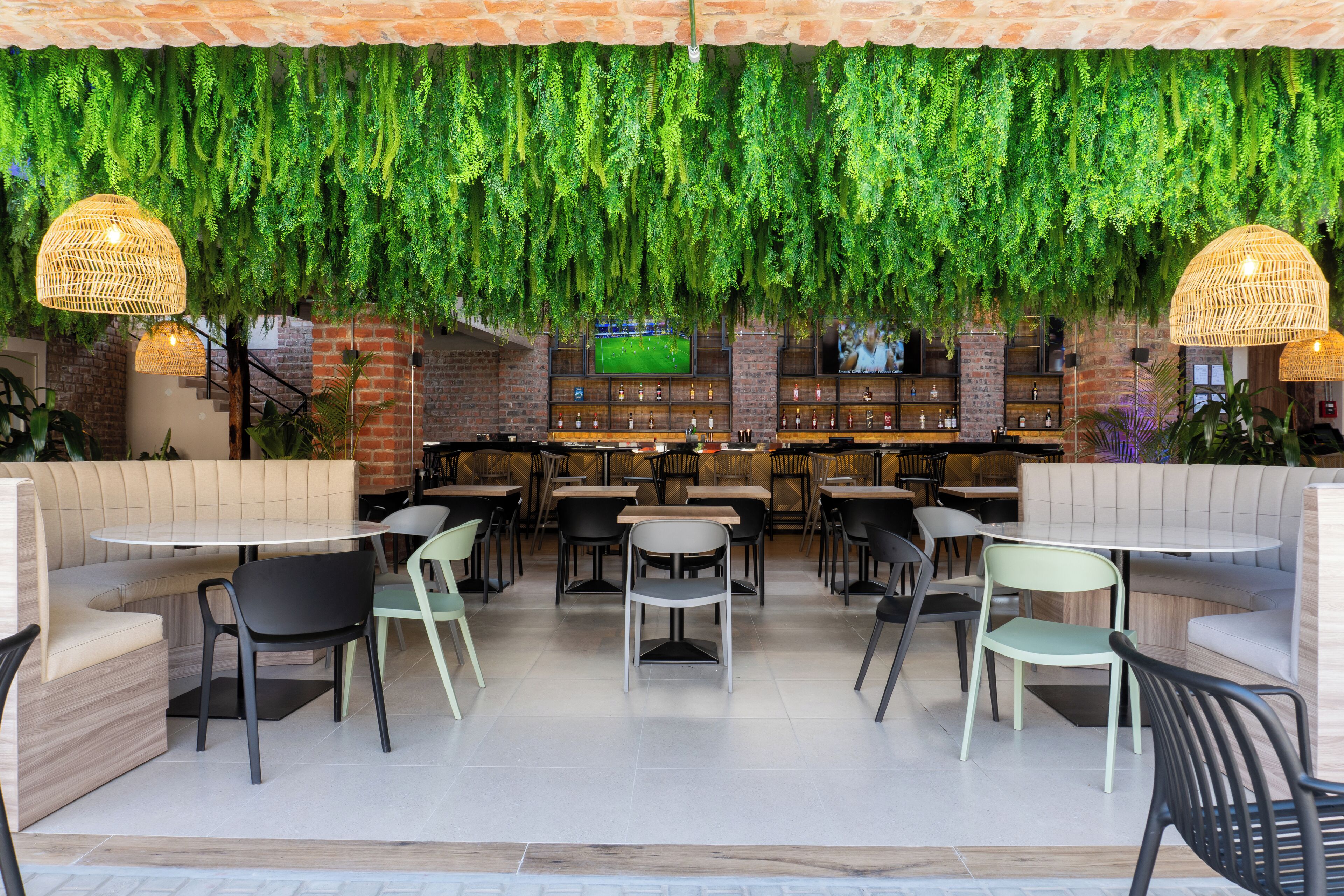 Un ristorante con banquette, tavoli e piante pensili.