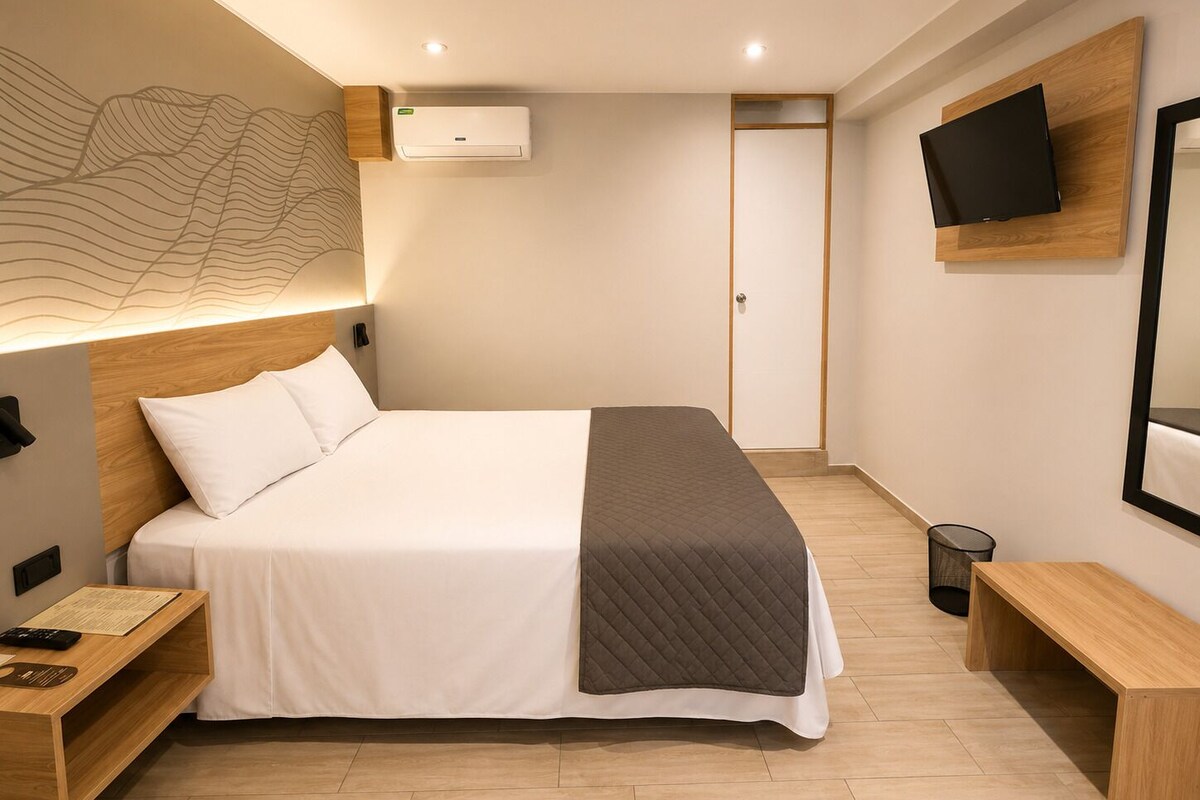 Quarto de hotel moderno com uma cama grande, mesas de cabeceira, uma TV de tela plana e ar-condicionado fixado na parede.