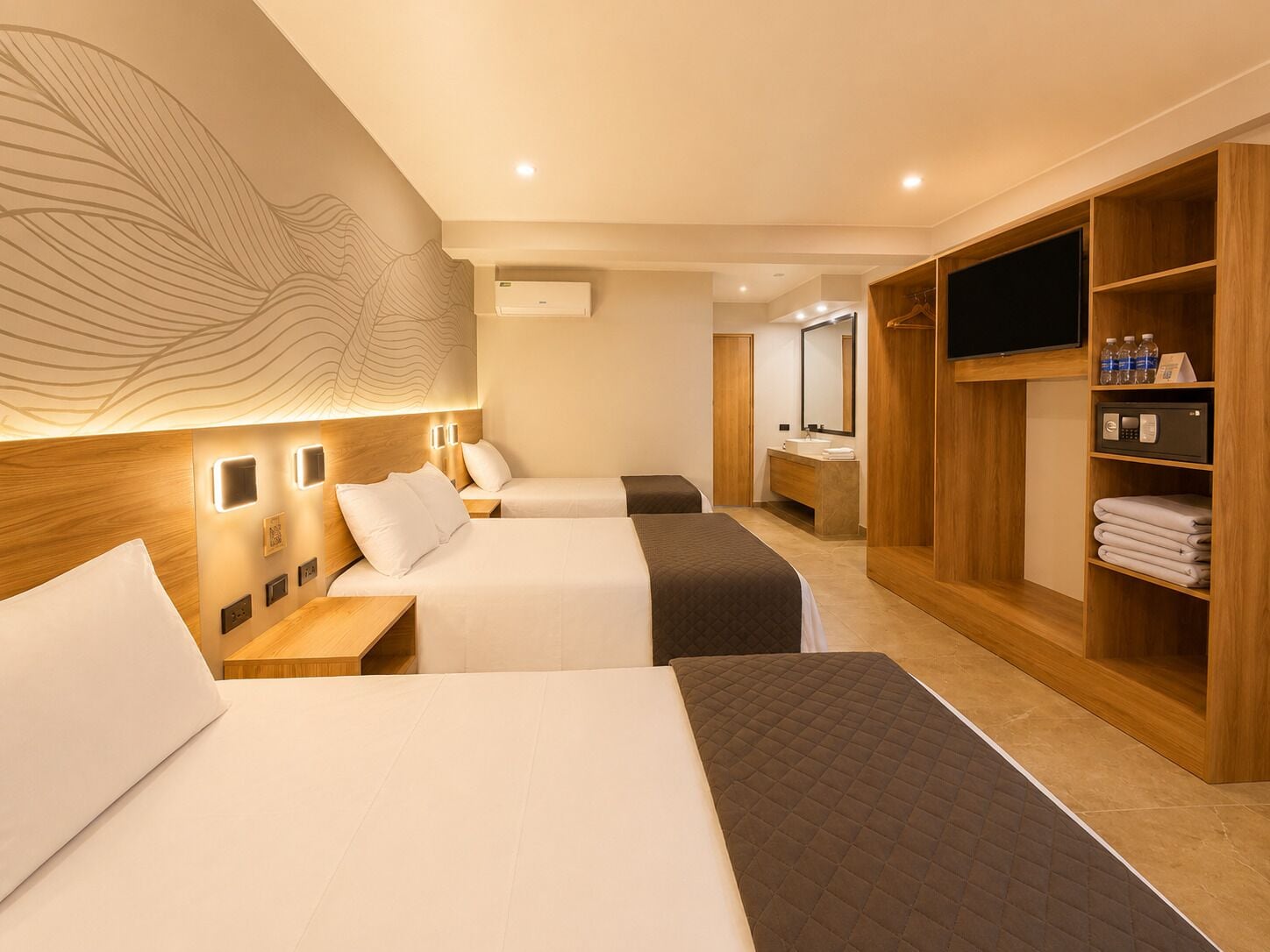 Habitación de hotel con dos camas, un armario de madera, un televisor y un baño con espejo.