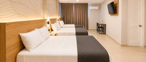 A hotel room with two beds, a desk, a TV, and a wall-mounted air conditioner.