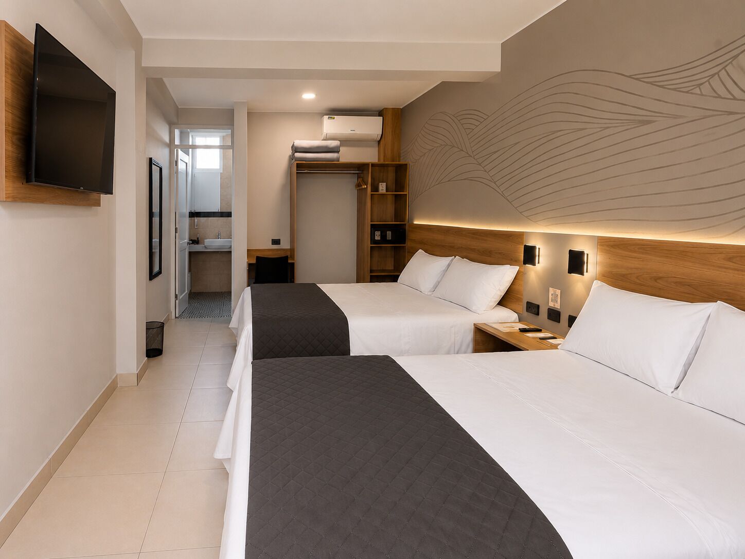 A hotel room with two beds, a TV, a wardrobe, and a bathroom.