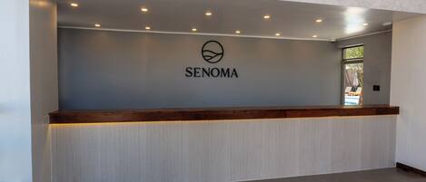 A reception desk with a logo, a wooden counter, and a textured wall.