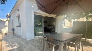 A patio with a table and chairs, a fan, and a large umbrella.