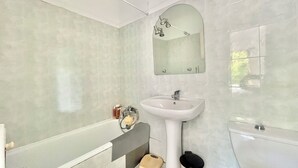 A bathroom with a white sink, a mirror, a toilet, and a bathtub.