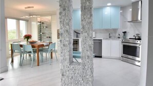 Une cuisine moderne avec des meubles de couleur bleu clair, un îlot central et des appareils électroménagers en acier inoxydable.