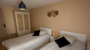 A hotel room with two single beds, a wardrobe, a lamp, and a wall decoration.