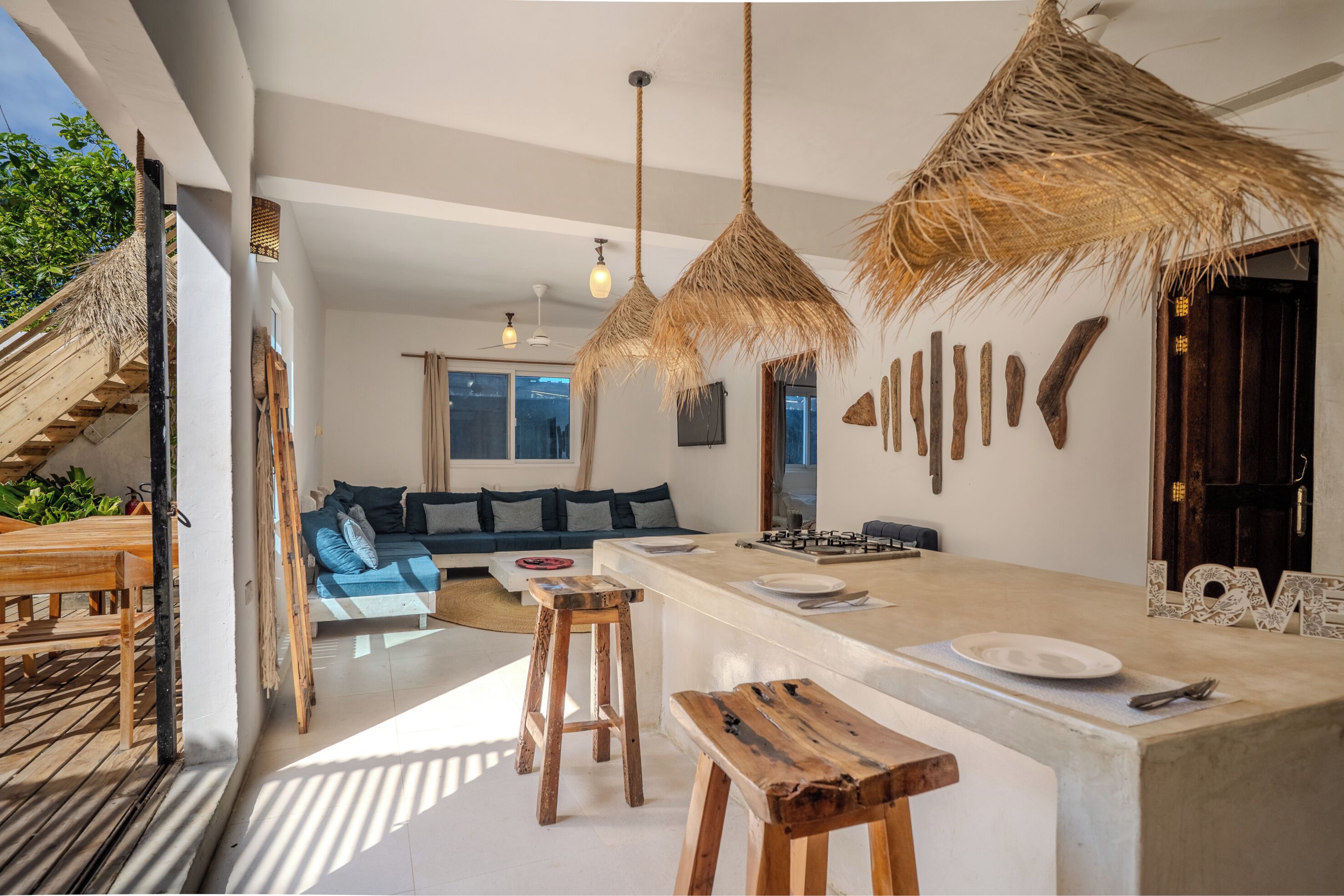 Een moderne keuken met een centraal eiland, houten krukken en een zithoek met een bank.