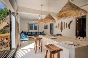 Une cuisine moderne dotée d’un îlot central, de tabourets en bois et d’un coin repas avec un canapé.