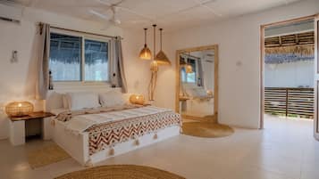 A bedroom with a bed, bedside lamps, a mirror, and a view of the outdoors.