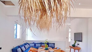 Un salon moderne avec une grande table centrale, un ensemble de canapés et une plante suspendue.
