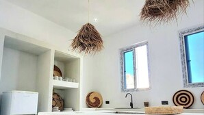 Une cuisine moderne avec des meubles blancs, un îlot central et deux luminaires suspendus.