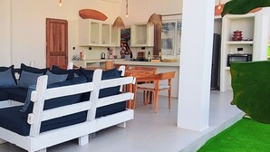 Un salon moderne avec un canapé, une table à manger et des luminaires suspendus.