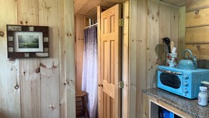 A rustic wooden interior with a kitchenette, a framed picture on the wall, and a blue kettle on the counter. - Fun Mountain Getaway with views and WIFI. Close to Mountains, Rivers and Lakes! (Wentworth)