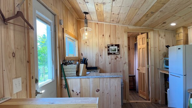 A wooden cabin interior with a kitchen area, including a countertop, sink, and refrigerator. - Fun Mountain Getaway with views and WIFI. Close to Mountains, Rivers and Lakes! (Wentworth)