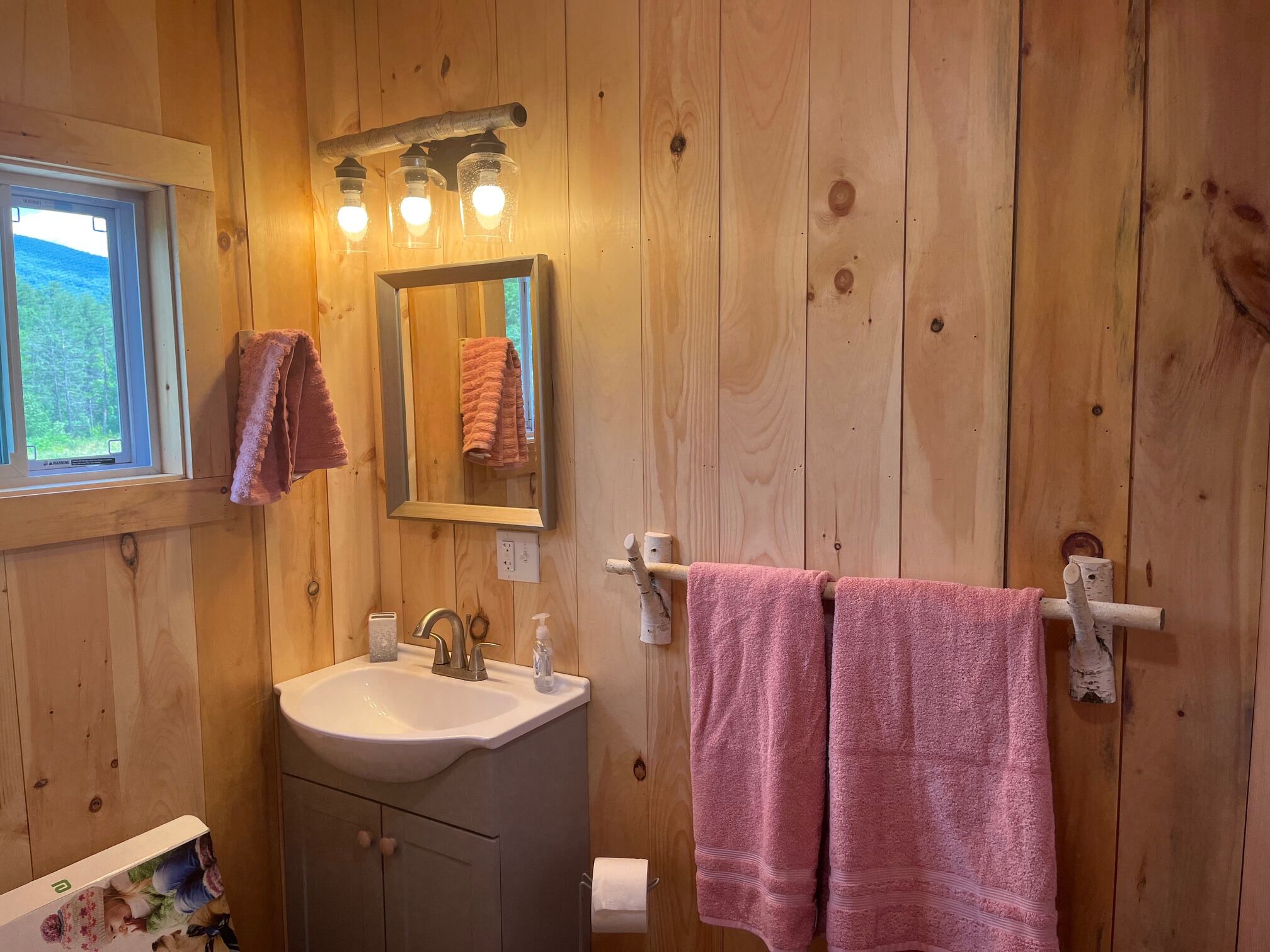 Un baño de madera con lavamanos, espejo y toallero.