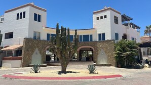 A two-story building with a central entrance, stone walls, and a cactus in the foreground.