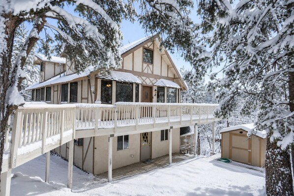 Un chalet à deux étages doté d’un balcon, entouré d’arbres couverts de neige.