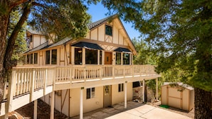 Ein zweistöckiges Haus mit Balkon, überdachter Veranda und einem kleinen Schuppen.