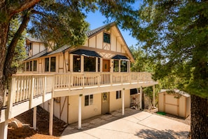 Une maison à deux étages avec un balcon, une véranda et un petit abri de jardin.